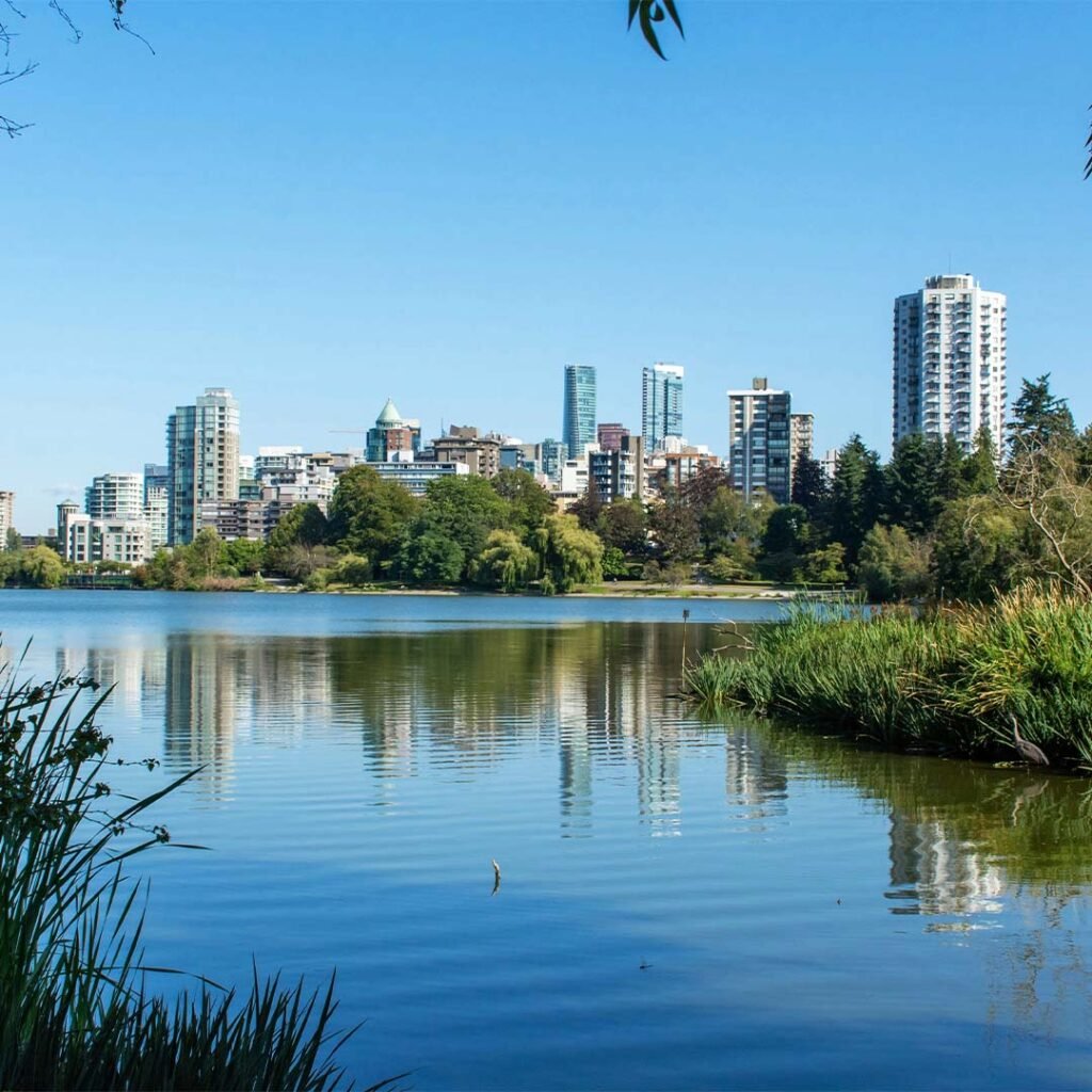 City skyline reflected on a lake under a clear blue sky