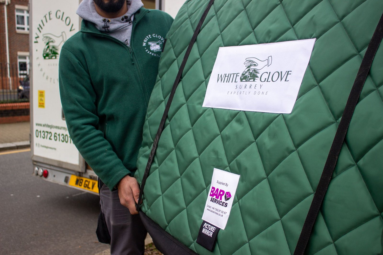 White Glove Surrey mover carrying a protected framed mirror